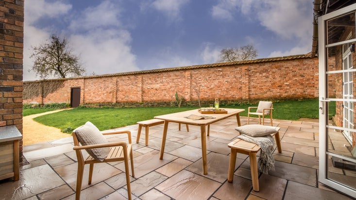 The patio with outdoor table and seating at The Weir Garden Cottage, Herefordshire